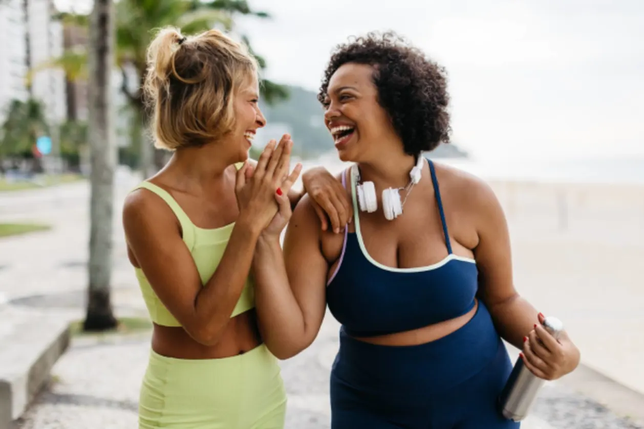 Two women laughing and high-fiving after a workout